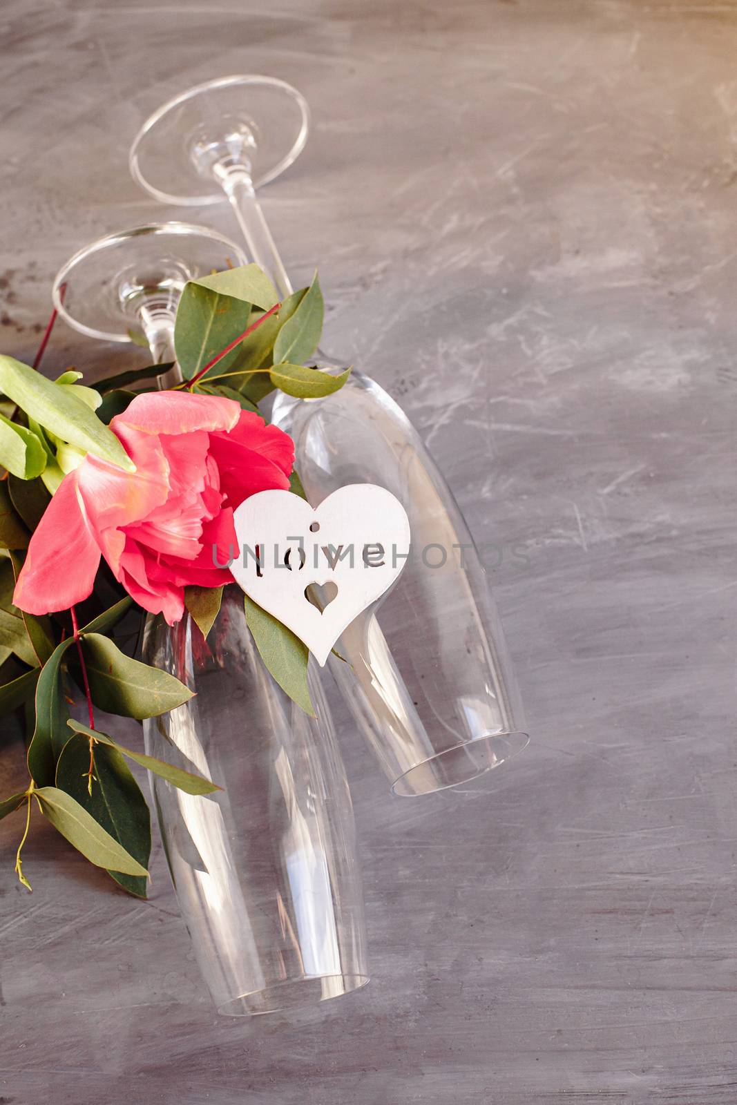 Composition with glass for champagne. Flowers and hearts on grey concrete background