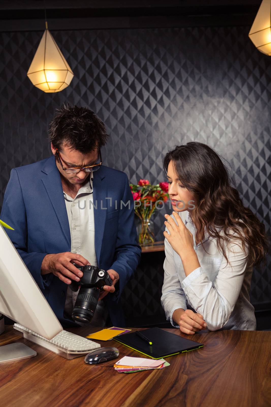 Creative business people looking at pictures on camera in office
