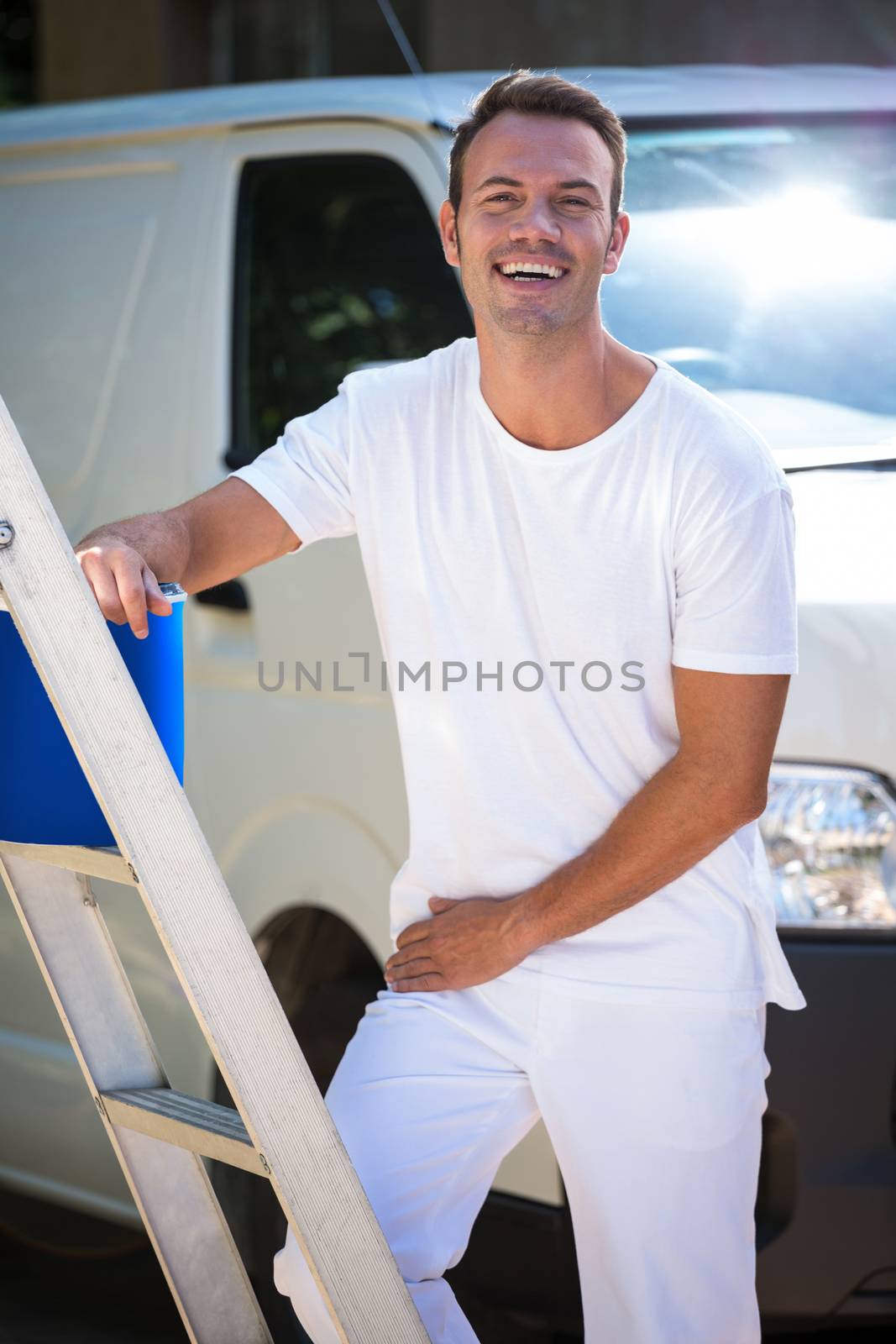 Portrait of painter with stepladder and bucket standing near his van