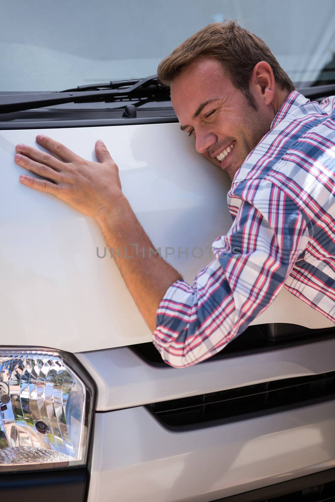 Happy young man hugging his car