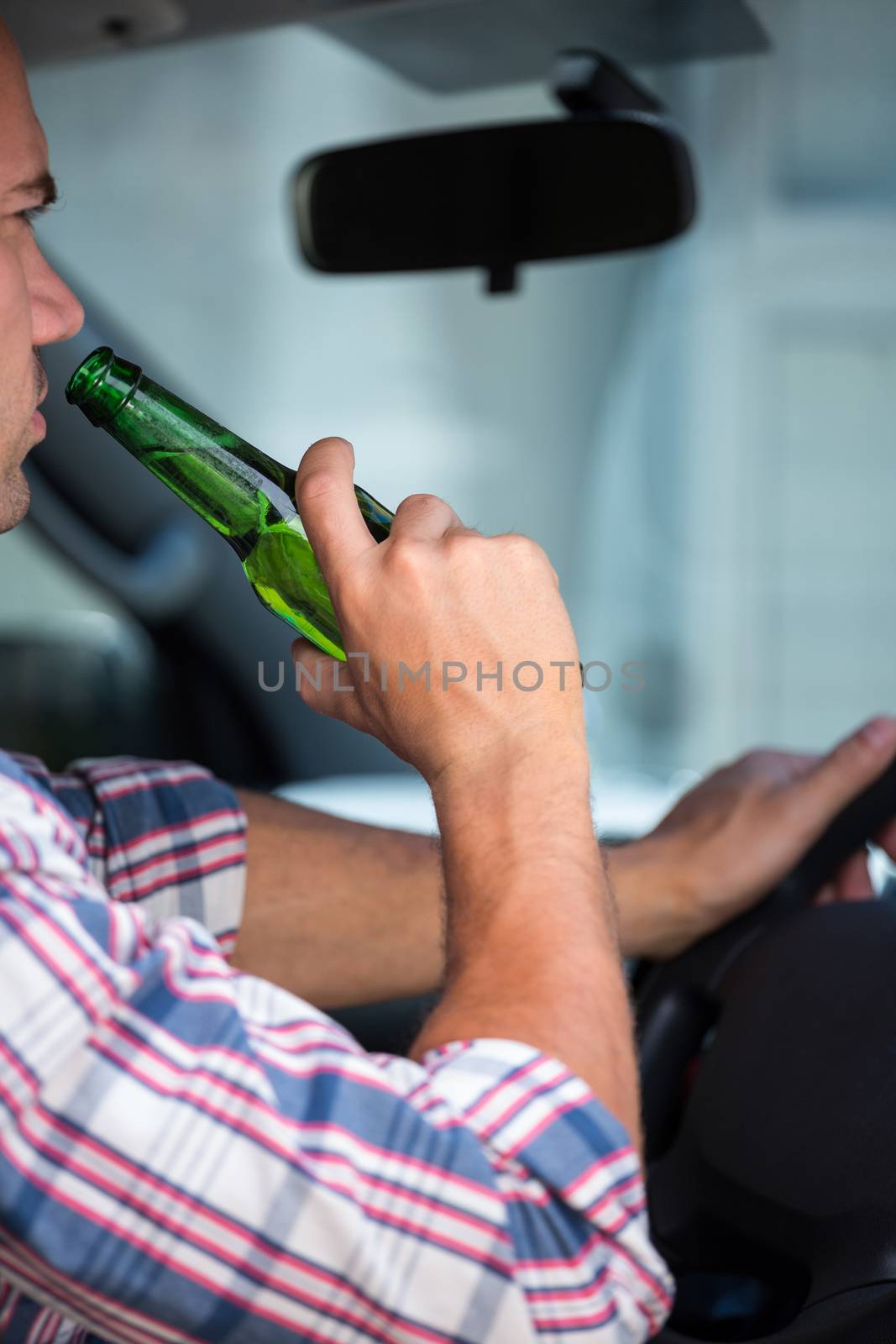 Man drinking beer while driving by Wavebreakmedia
