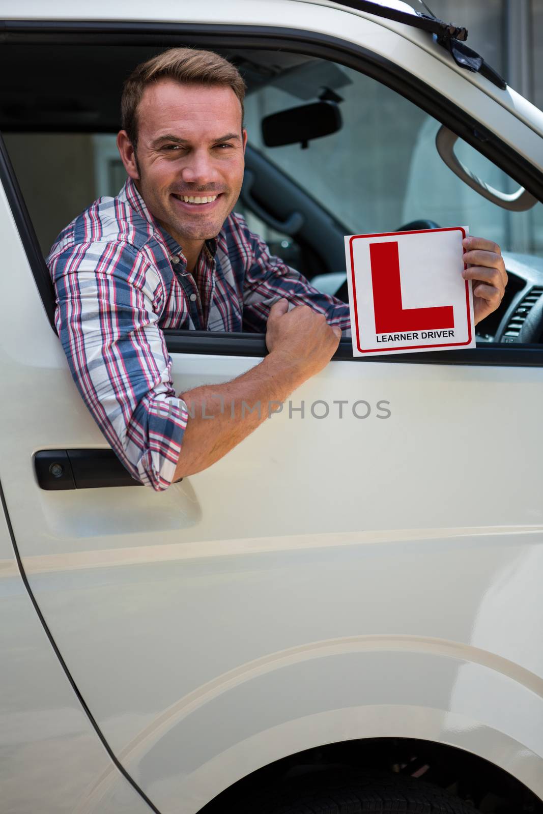 Portrait of young man holding a learner driver sign