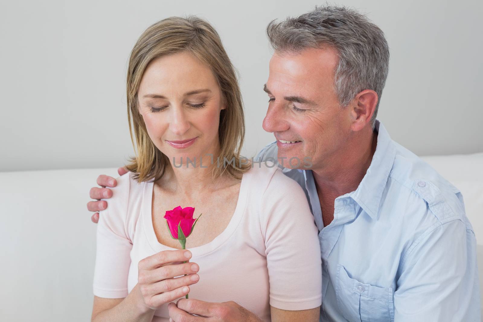 Portrait of a happy romantic couple with a flower at home