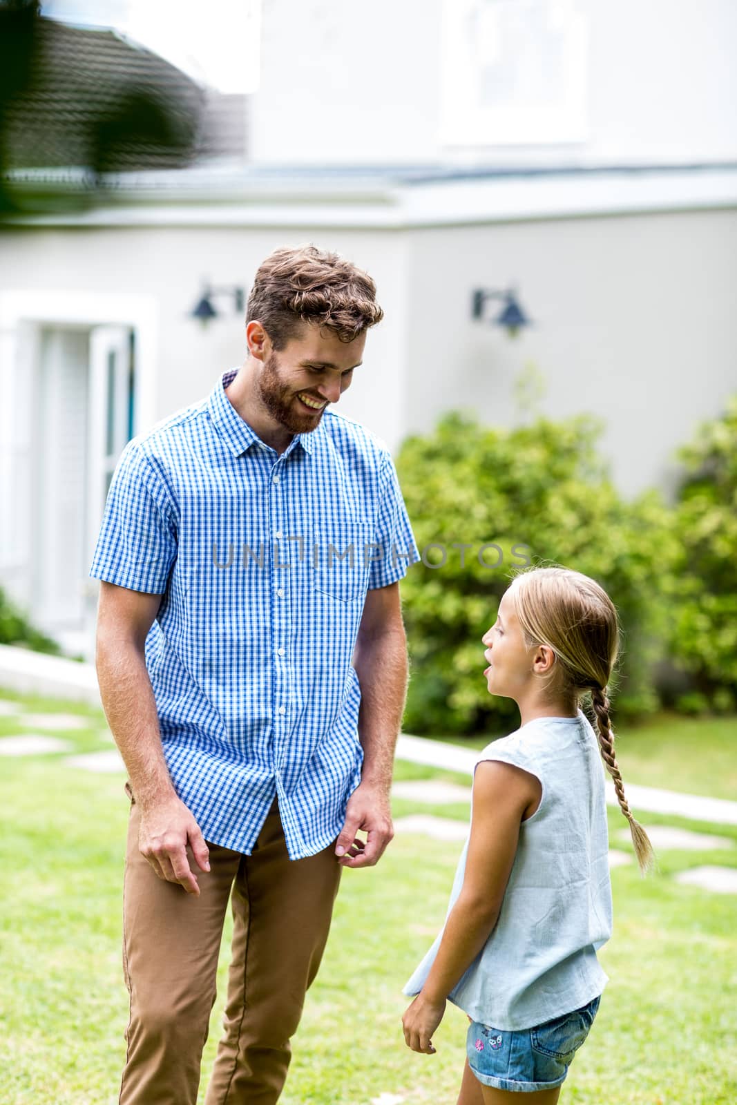 Smiling father standing with daughter in yard 