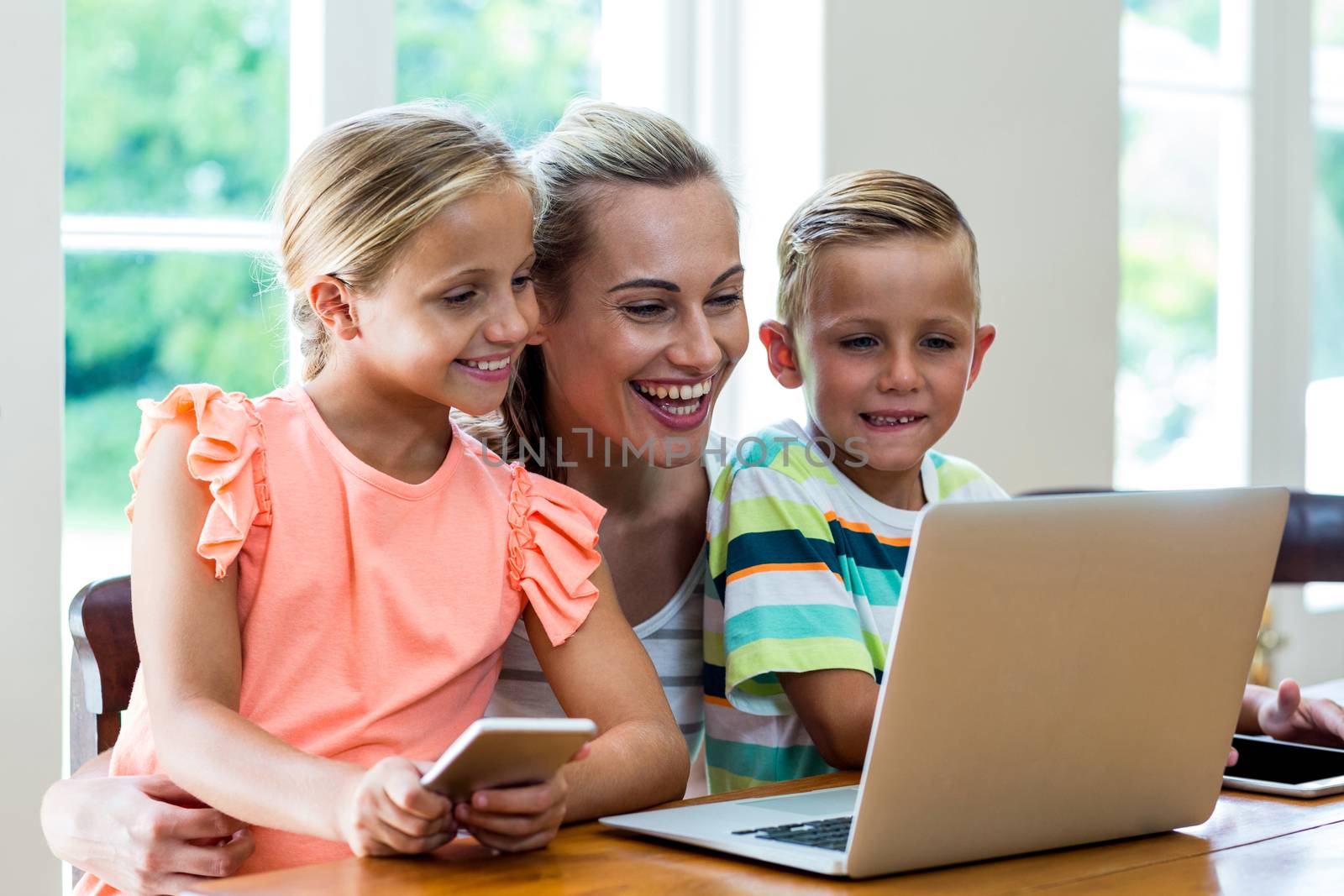 Smiling mother and children looking at laptop   by Wavebreakmedia
