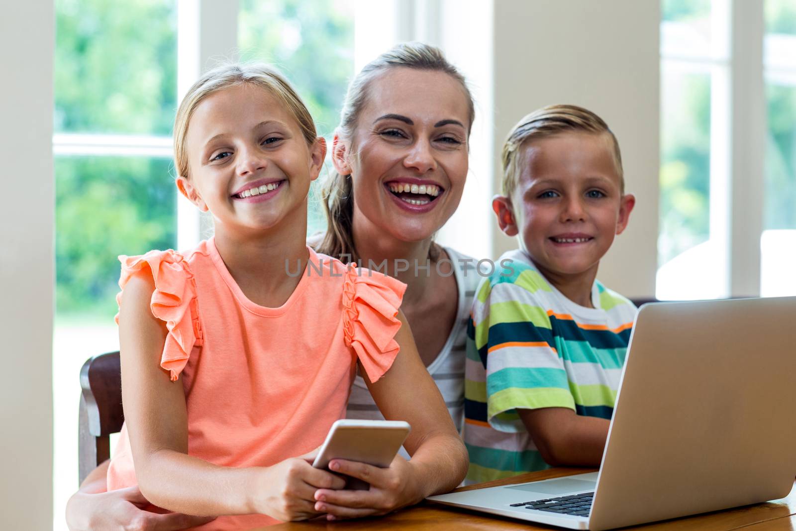 Portrait of smiling mother with children holding technologies at home 