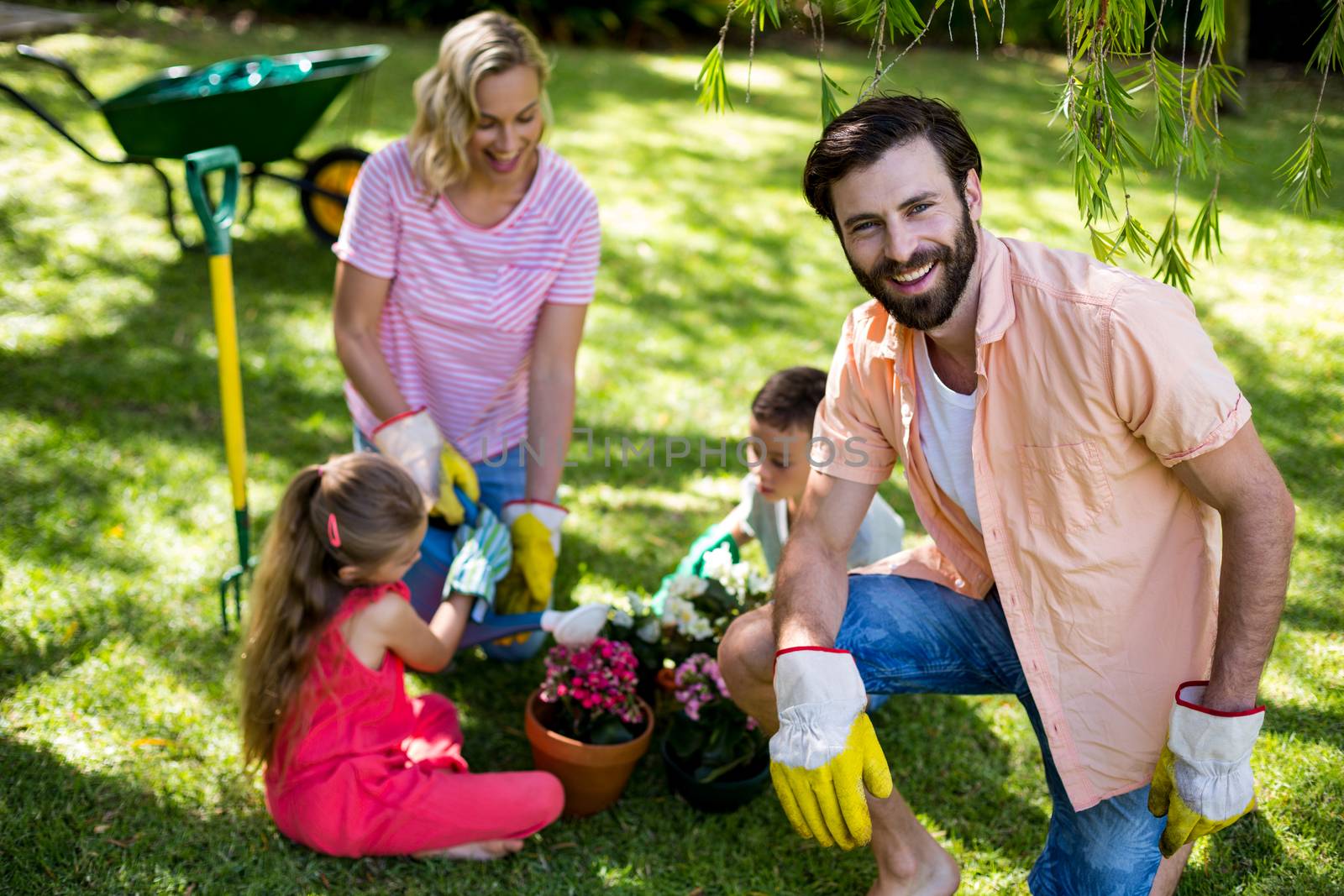Smiling father against family during gardening in yard 