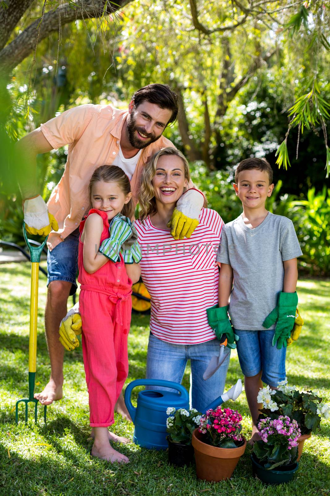 Portrait of happy family with gardening equipment in yard 