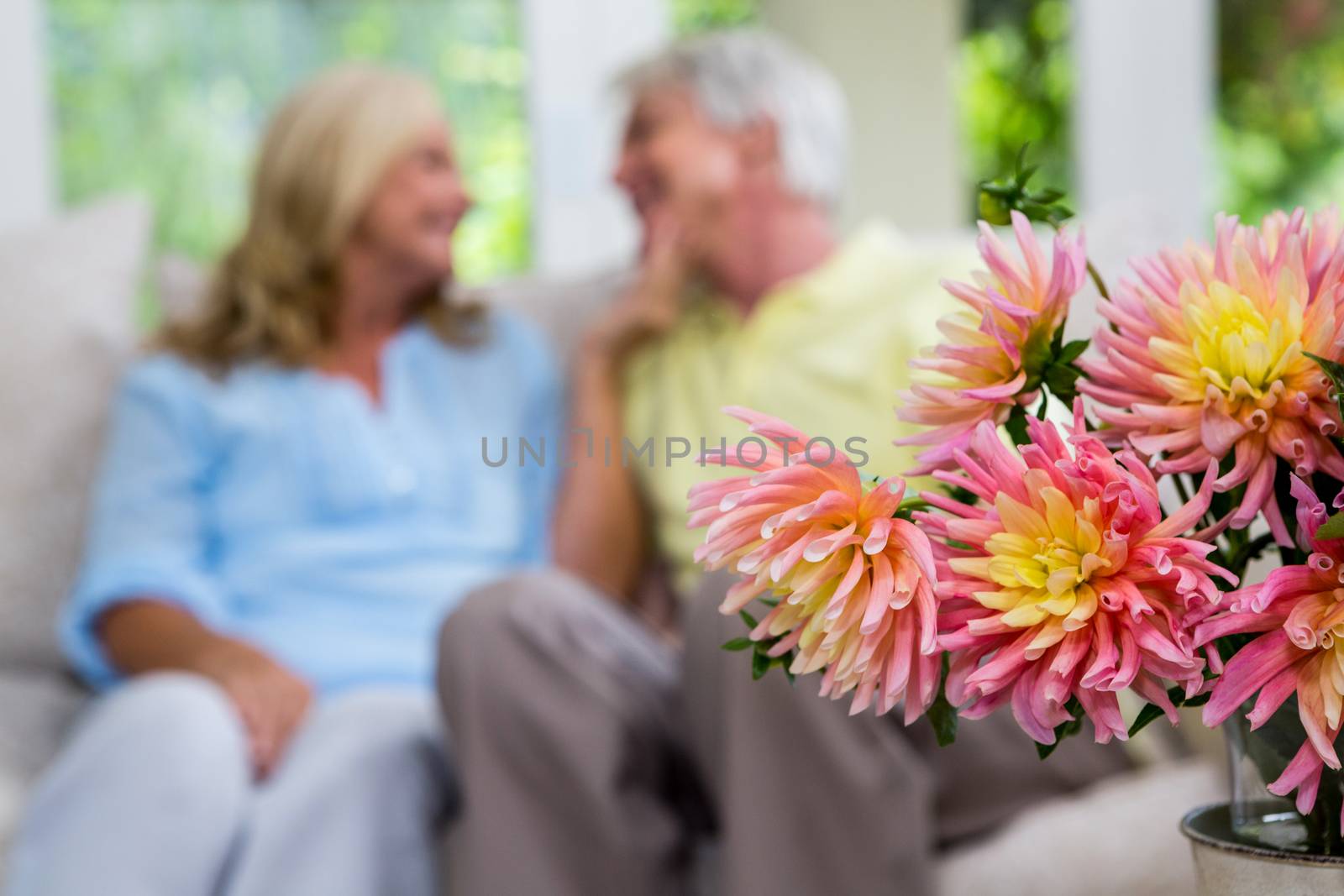 Flower vase with romantic senior couple in background sitting at home