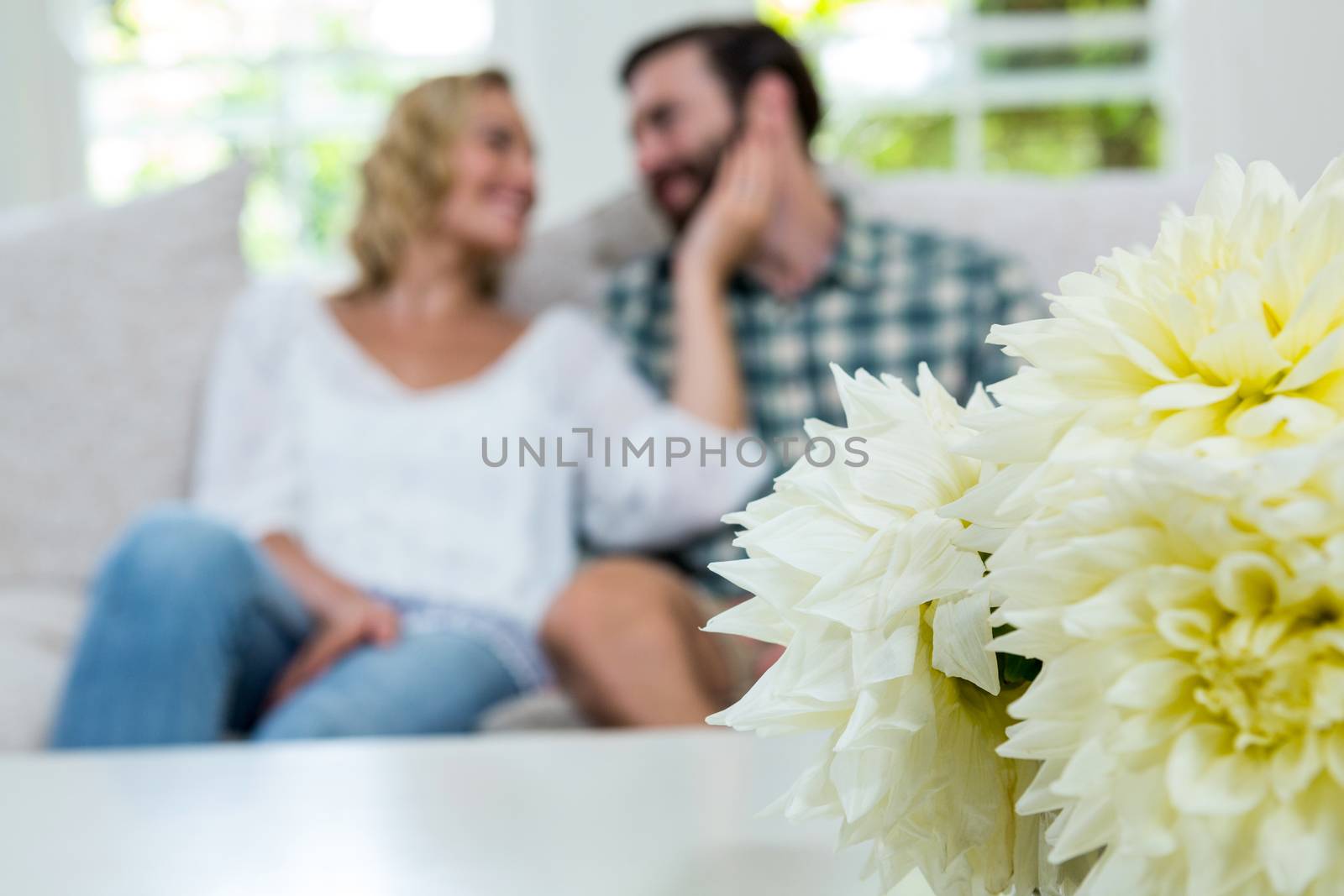 Close-up of dahlias on table against romantic couple at home