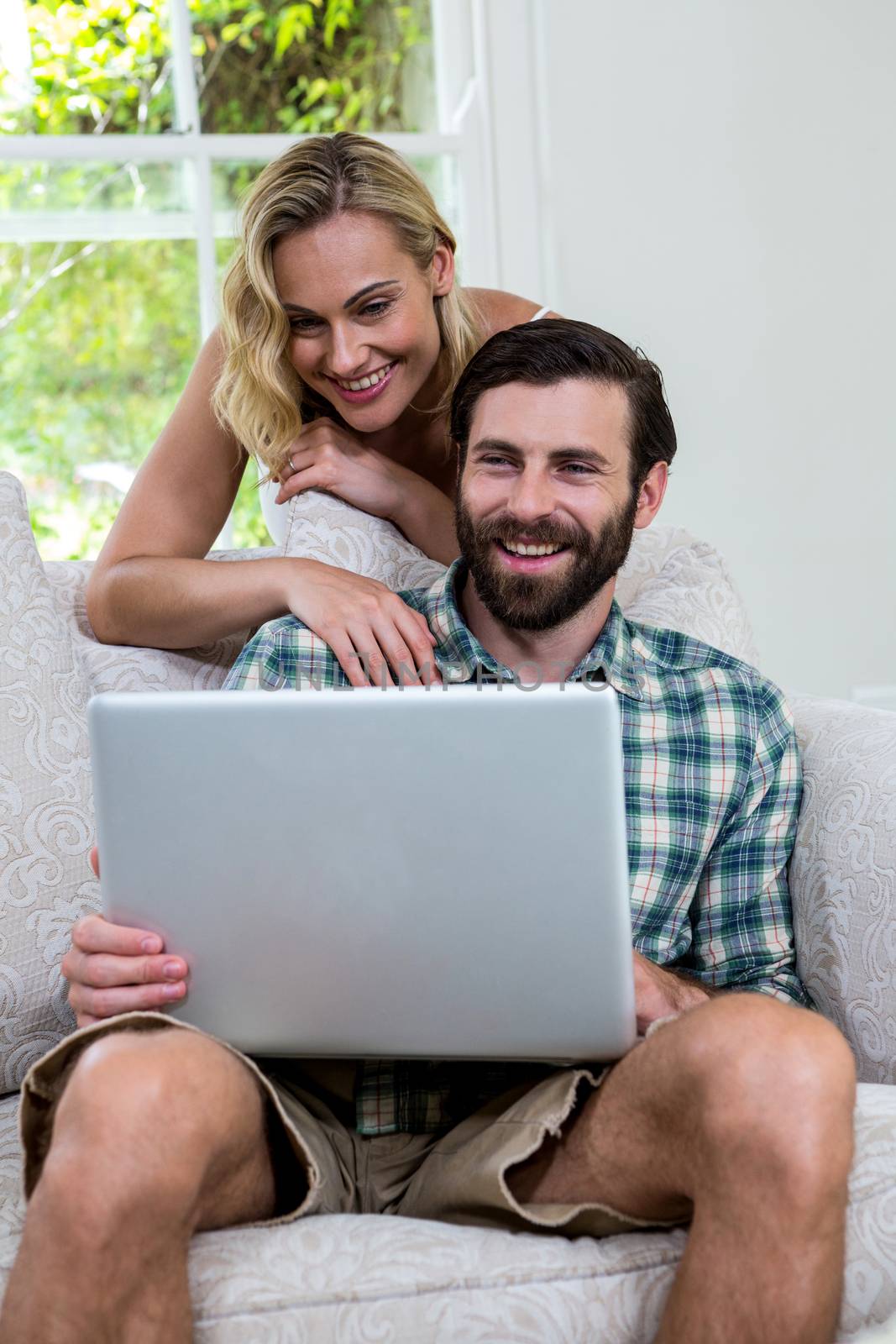 Happy couple with laptop in living room by Wavebreakmedia