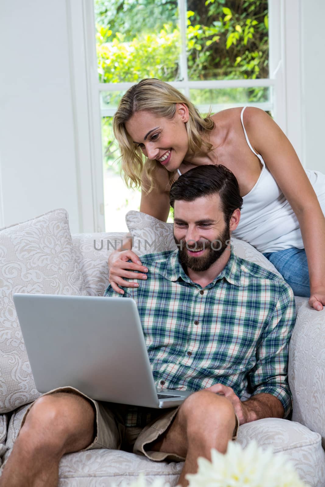 Happy couple using laptop in sitting room at home