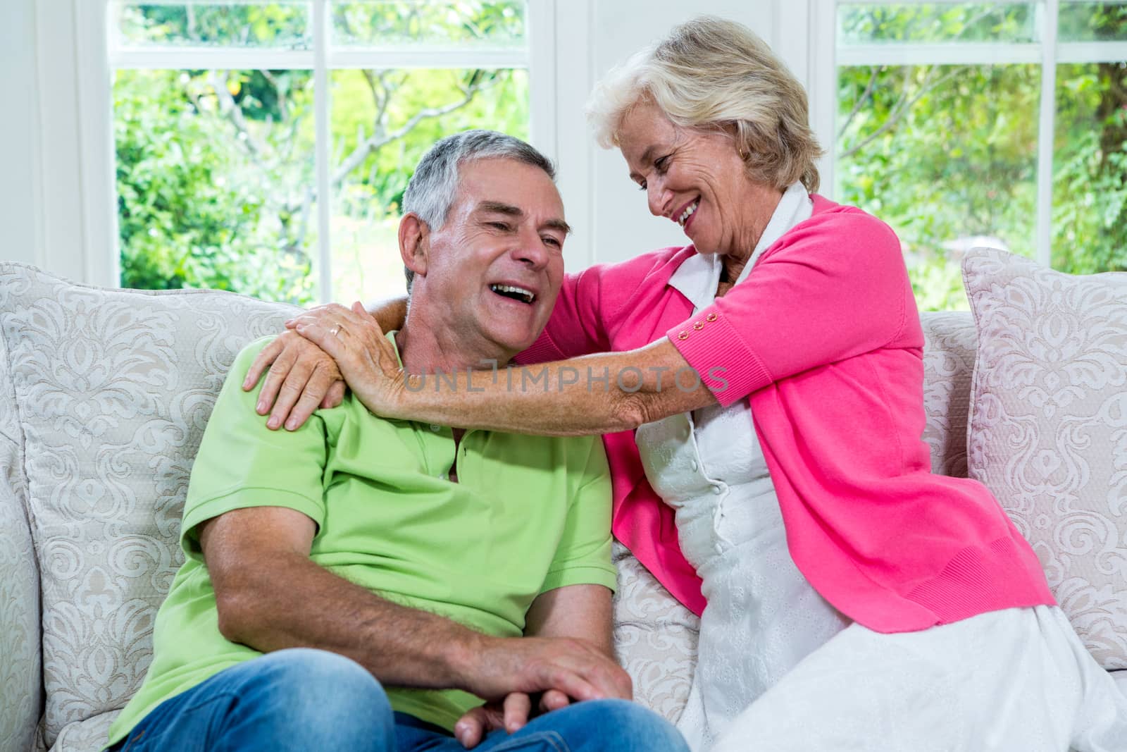 Romantic senior woman laughing with husband on sofa by Wavebreakmedia