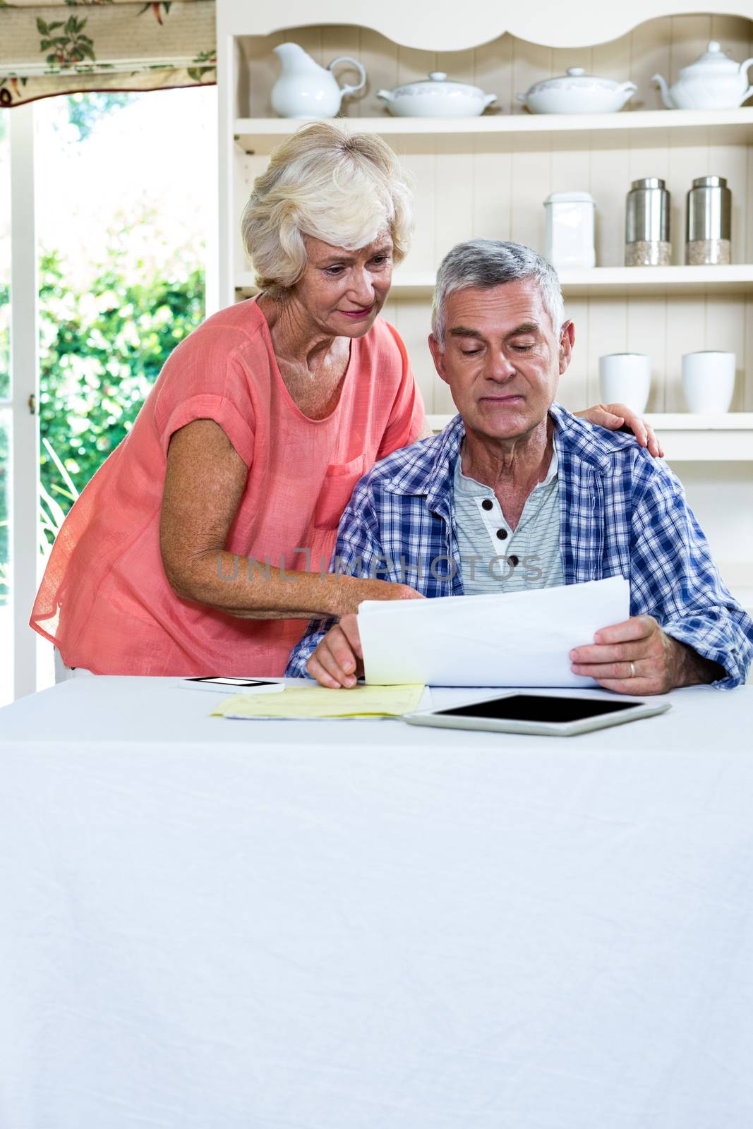 Wife discussing with senior man on documents at table against shelves