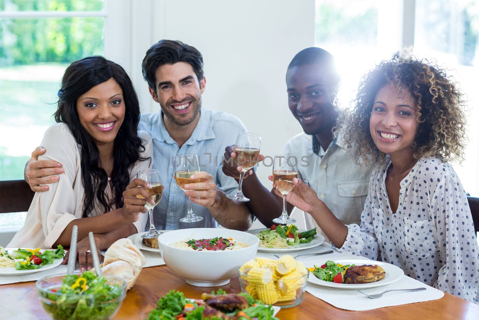 Two couples holding wine glass while having meal by Wavebreakmedia