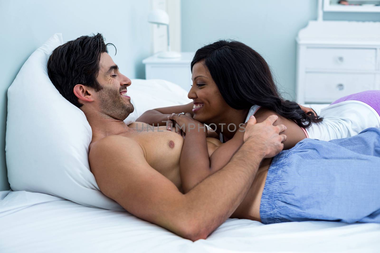 Romantic couple lying together on bed in bedroom