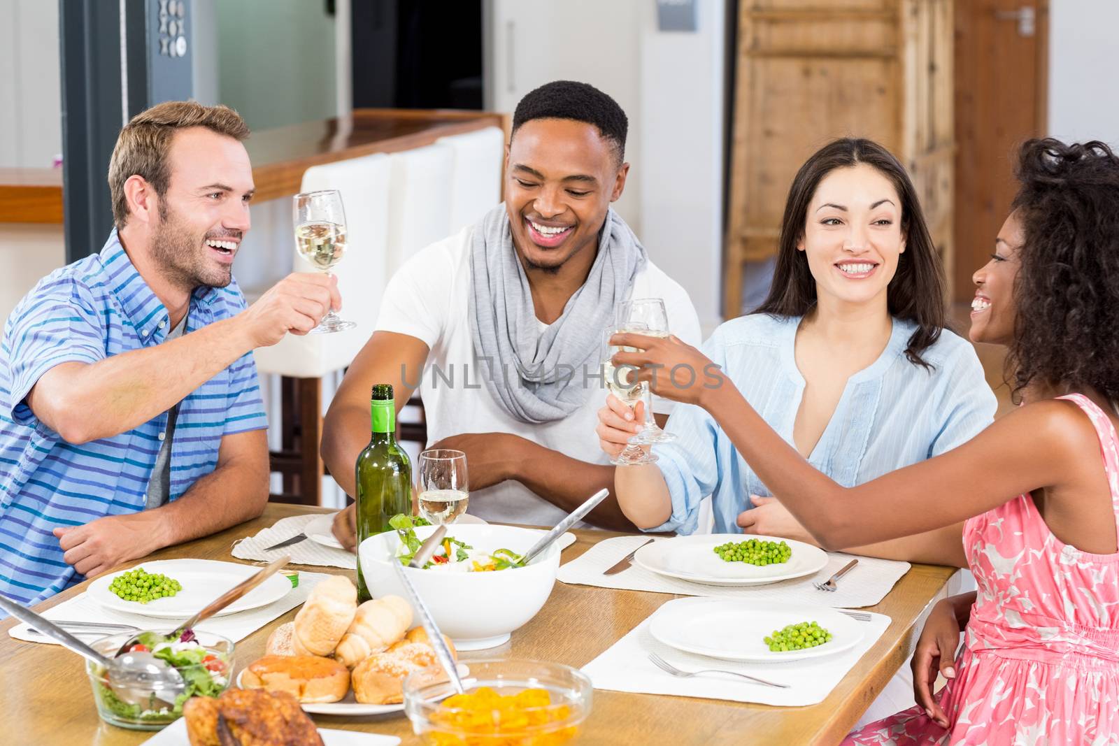 Friends toasting wine glasses while having a meal by Wavebreakmedia