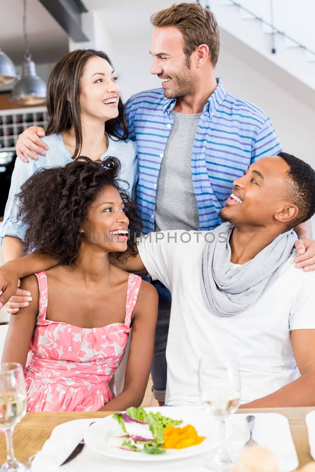 Friends looking at each other and smiling in dining room