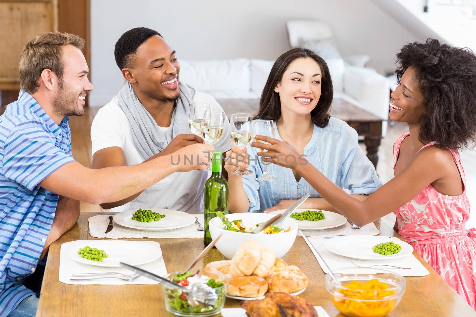 Friends toasting wine glasses while having a meal by Wavebreakmedia