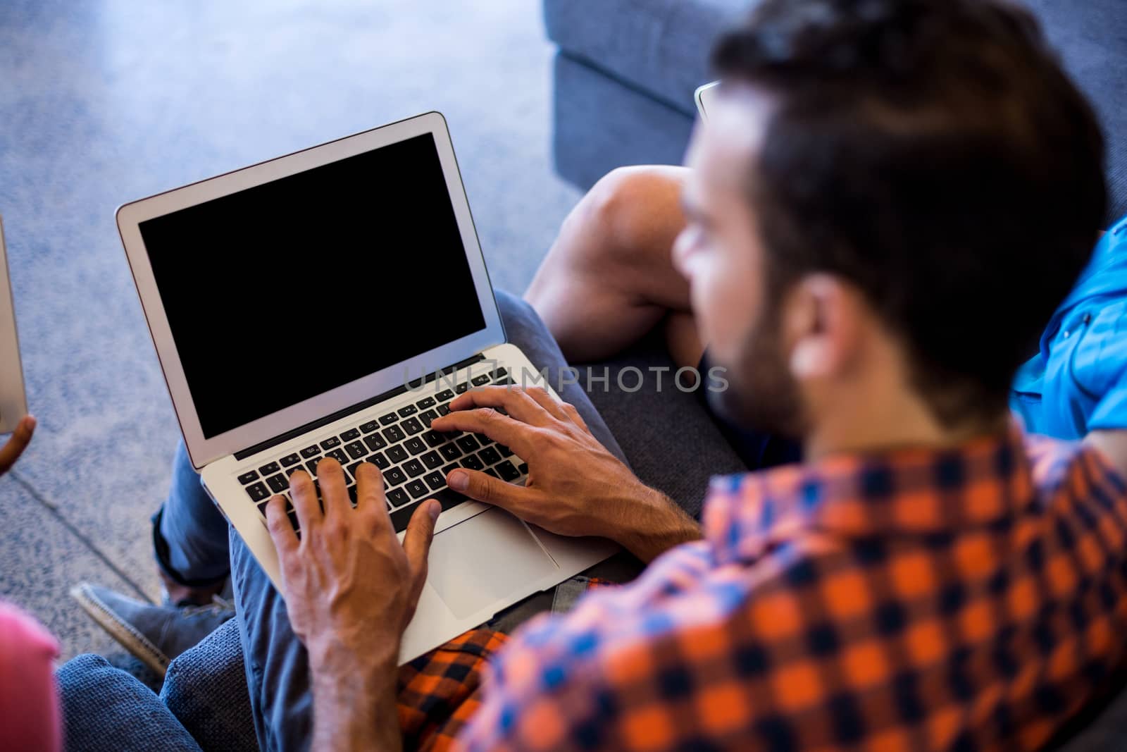 Man siting on sofa using laptop by Wavebreakmedia