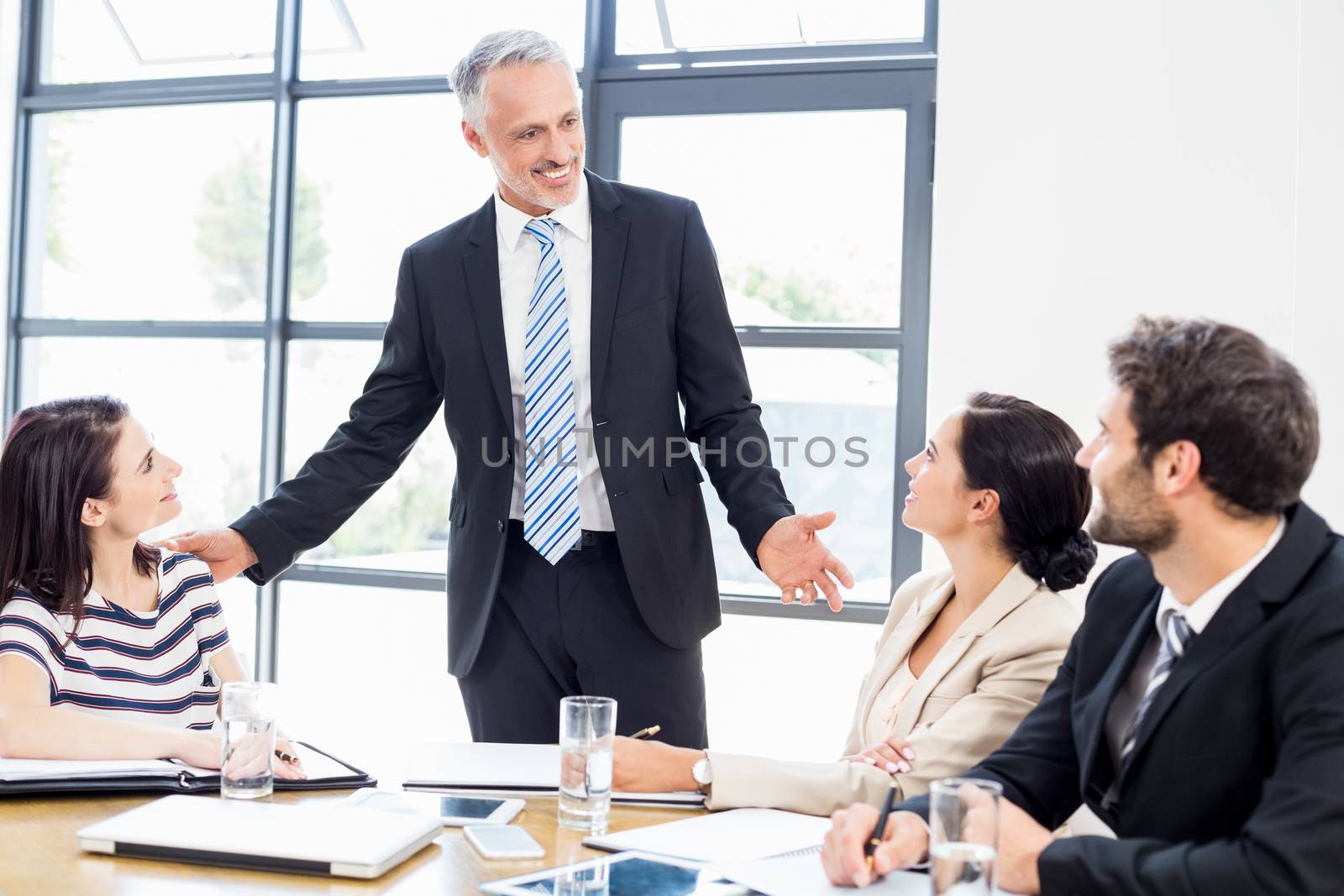 A businessman is talking to his colleagues and all are smiling at work