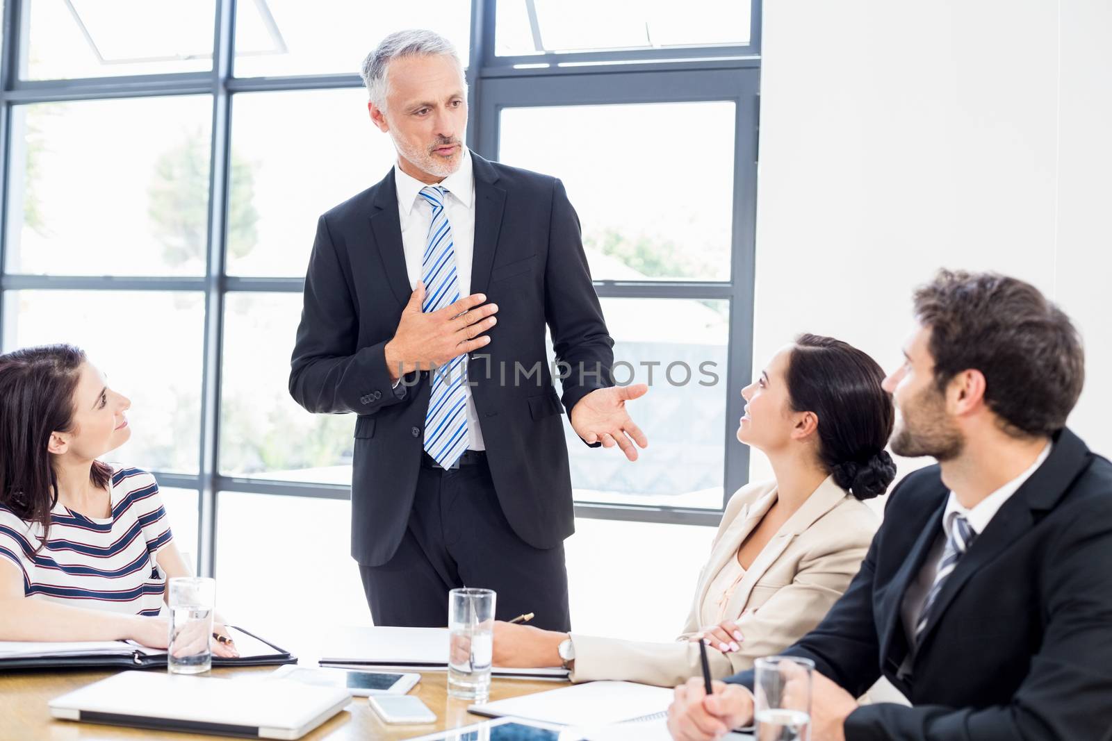A businessman is standing in front of his colleagues and talking at work