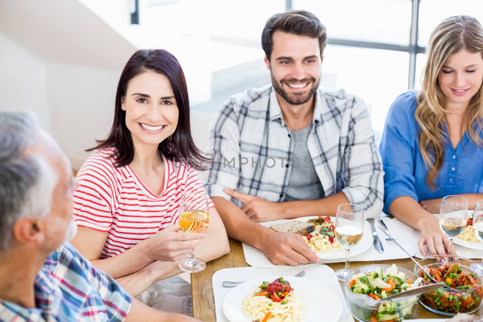 Woman sitting with friends at dinning table by Wavebreakmedia