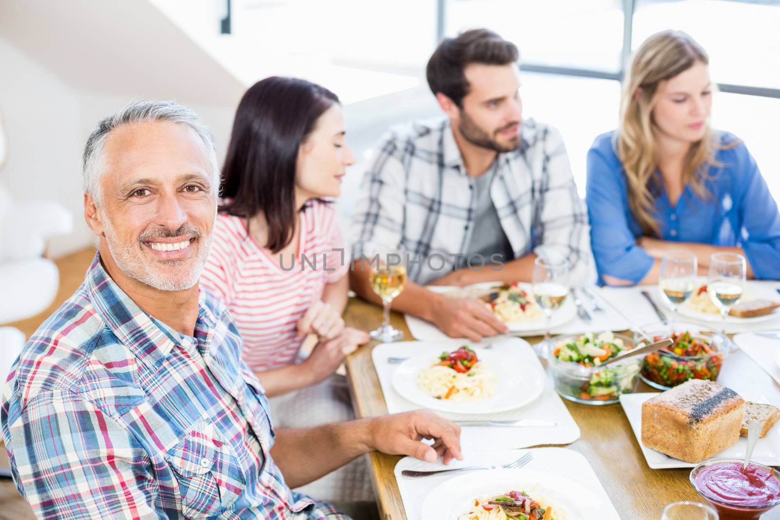 Man sitting with friends at dinning table by Wavebreakmedia