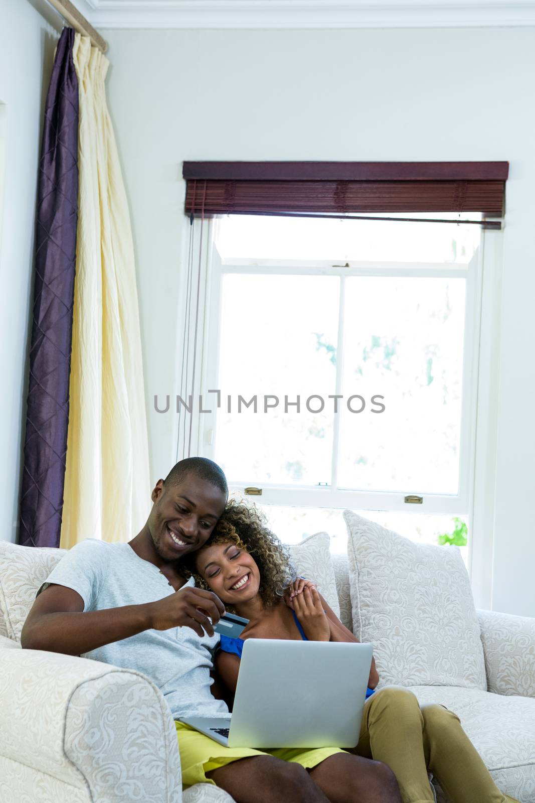 Young couple doing online shopping on laptop in living room by Wavebreakmedia