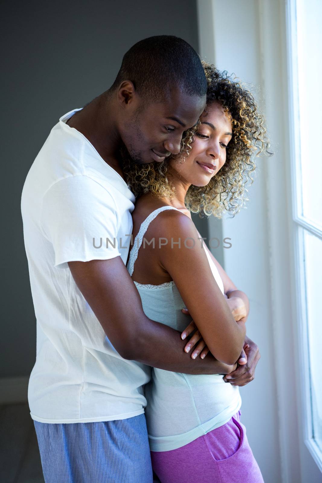 Young couple embracing near window at home