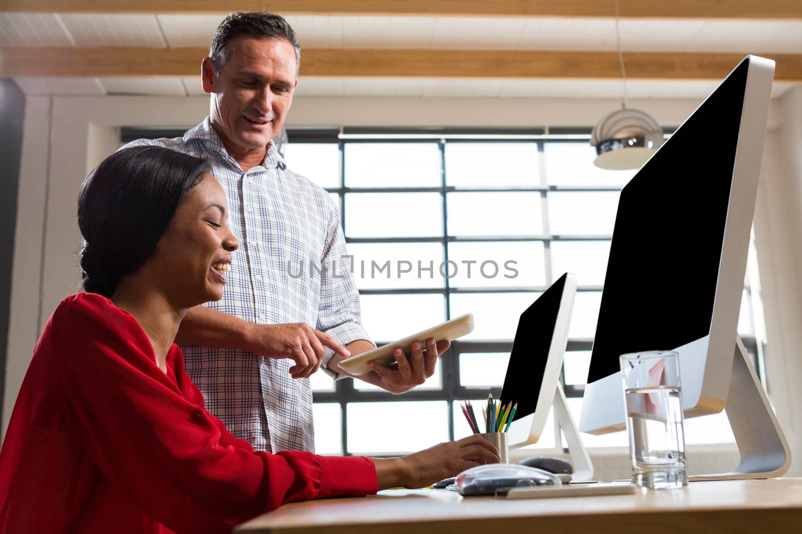 Colleagues looking at digital tablet and discussing in the office