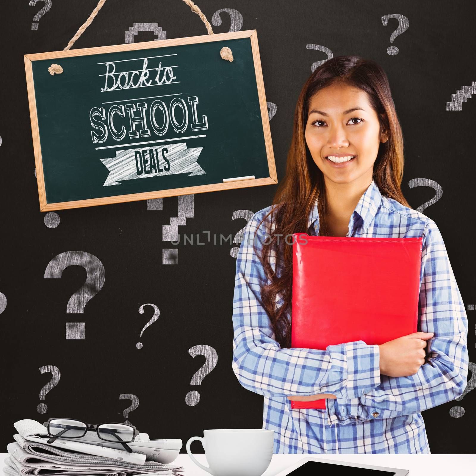 Smiling asian woman holding red book against blackboard