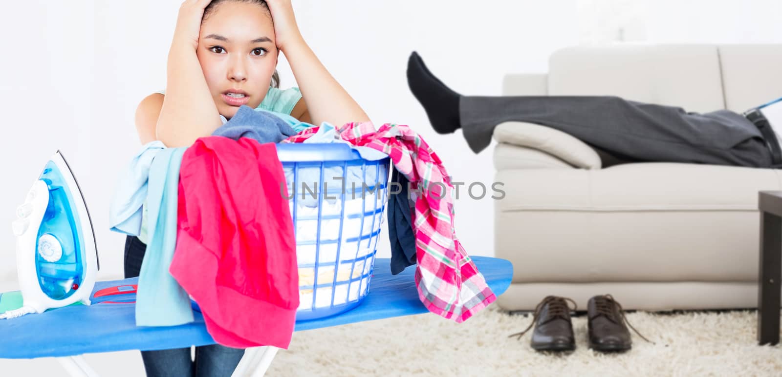 Woman fed up with ironing against low section of a businessman resting on sofa in living room