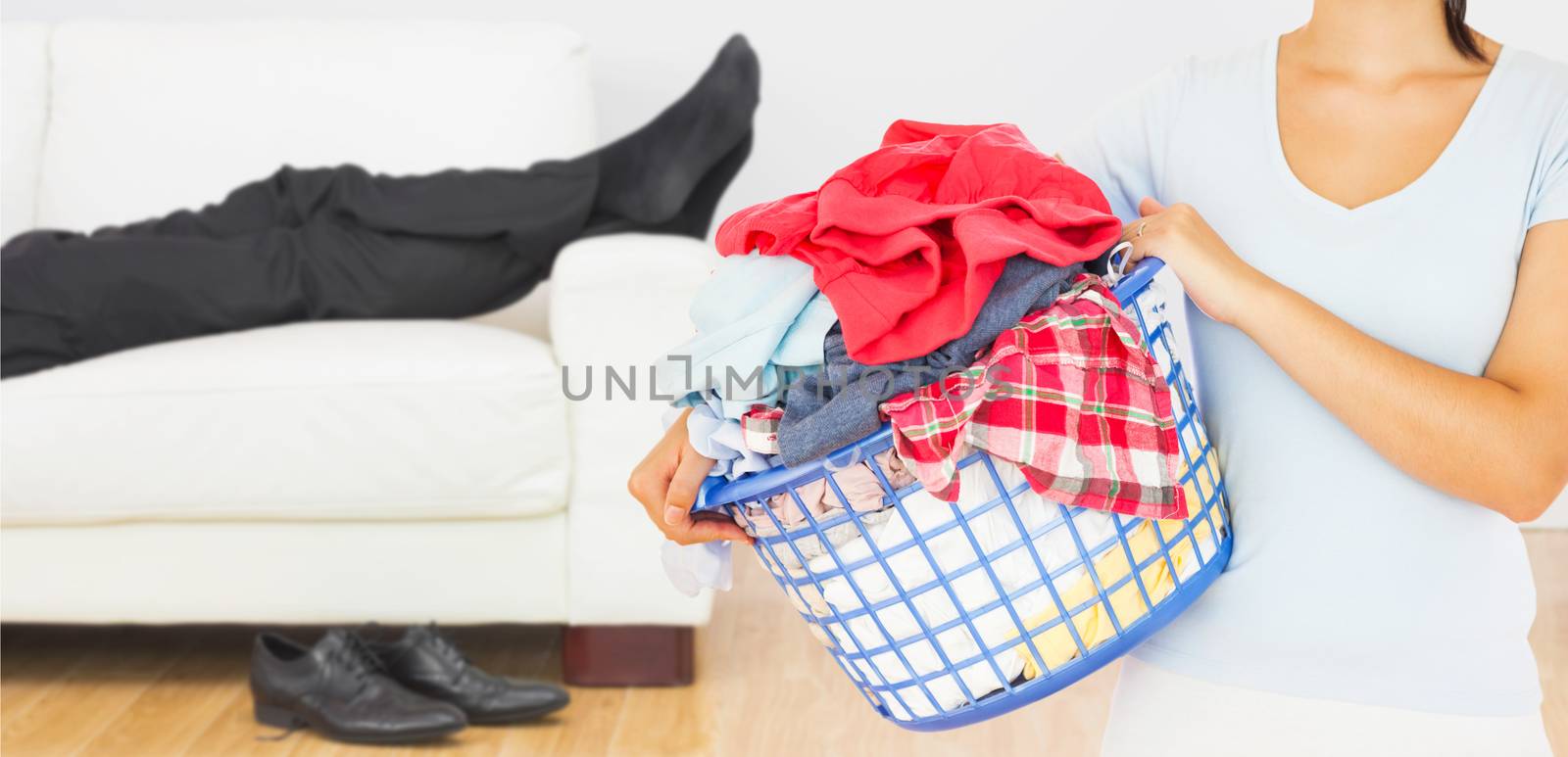 Composite image of brunette holding a basket full of laundry by Wavebreakmedia