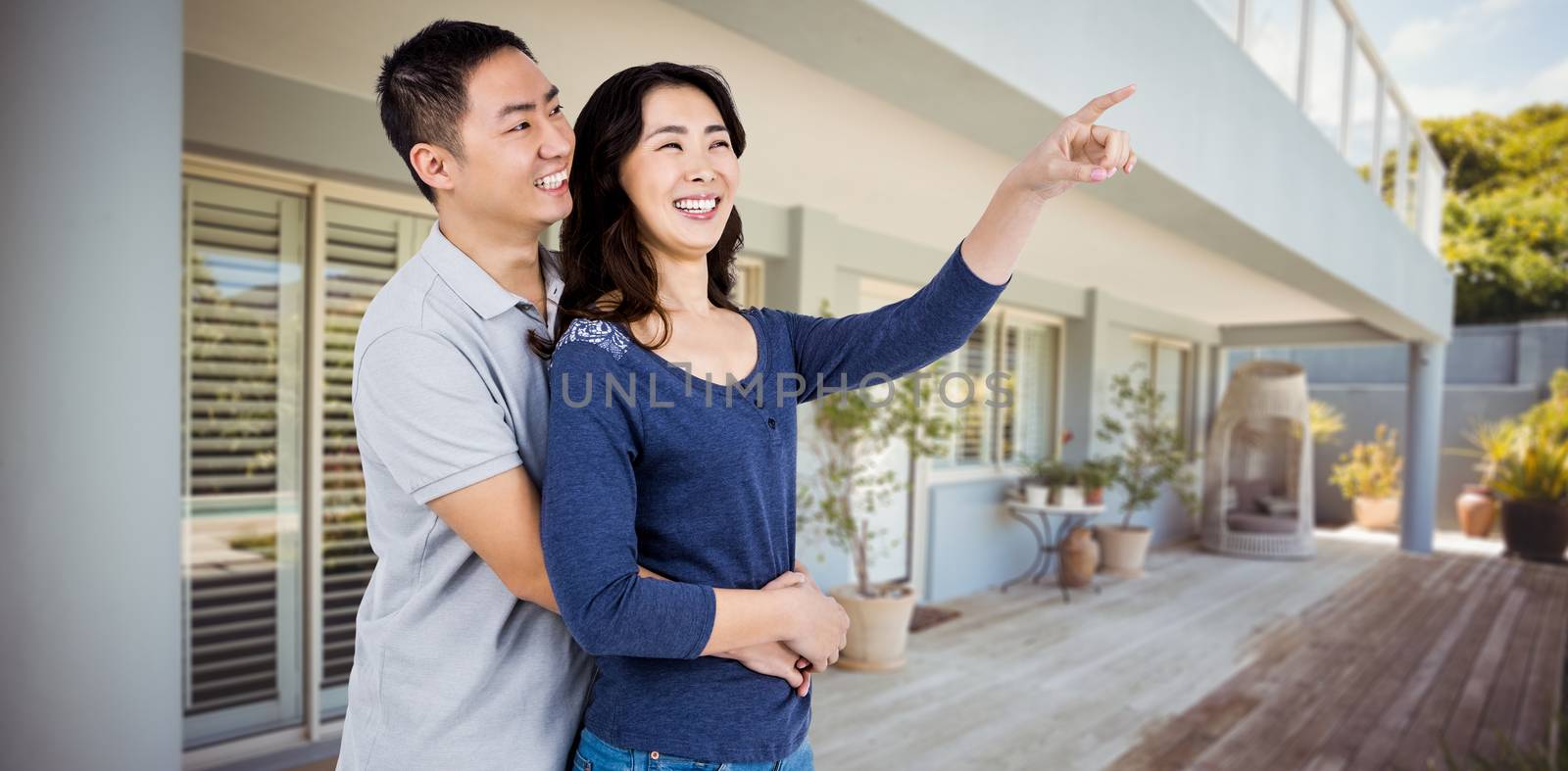 Happy couple with woman pointing up against stylish outdoor patio area