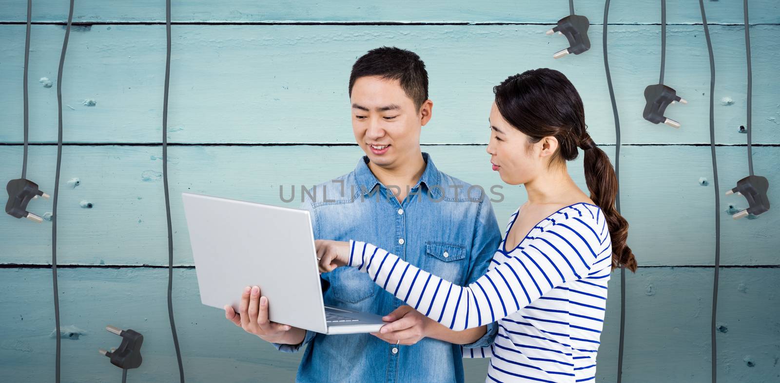 Couple using laptop against plugs on wooden background