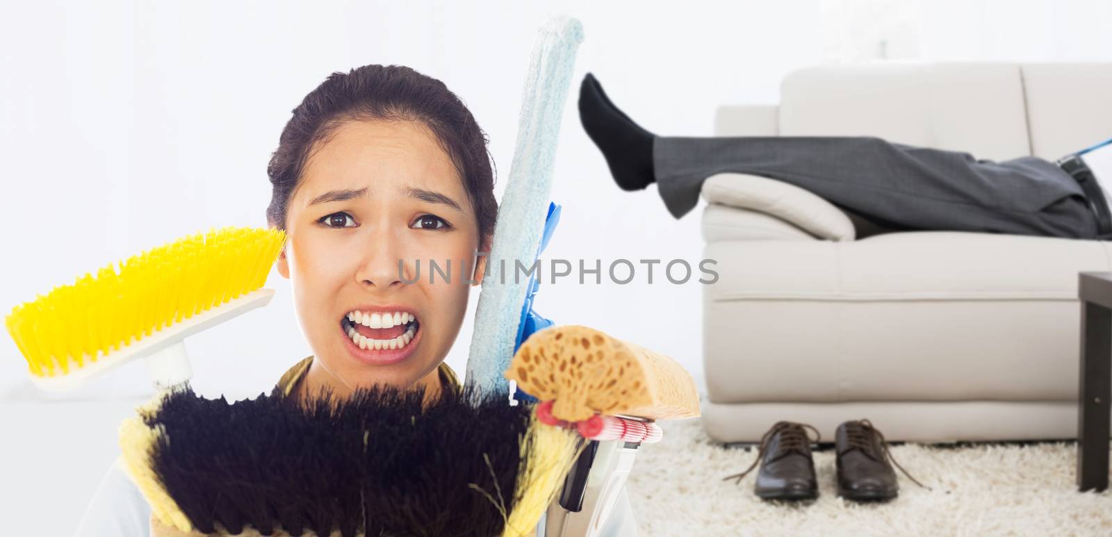 Very stressed woman with cleaning tools against low section of a businessman resting on sofa in living room