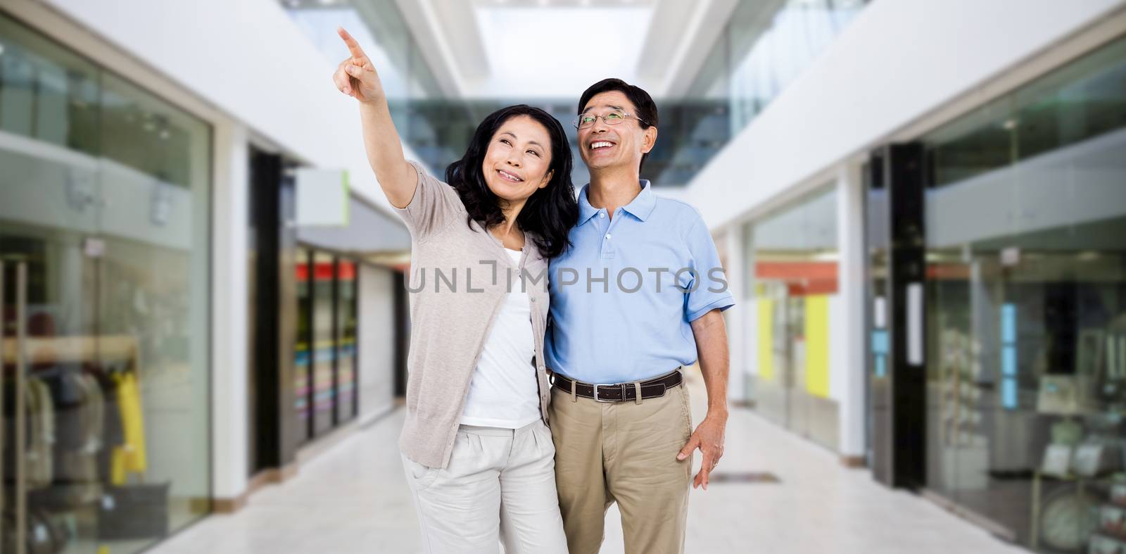 Smiling couple holding each other against interior of modern shopping mall