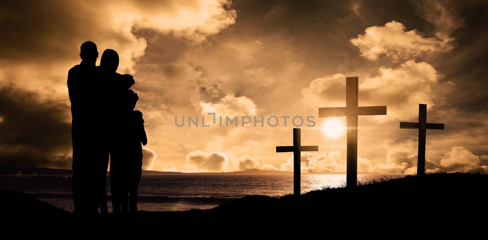 Happy family embracing each other over against cross religion symbol shape over sunset sky 