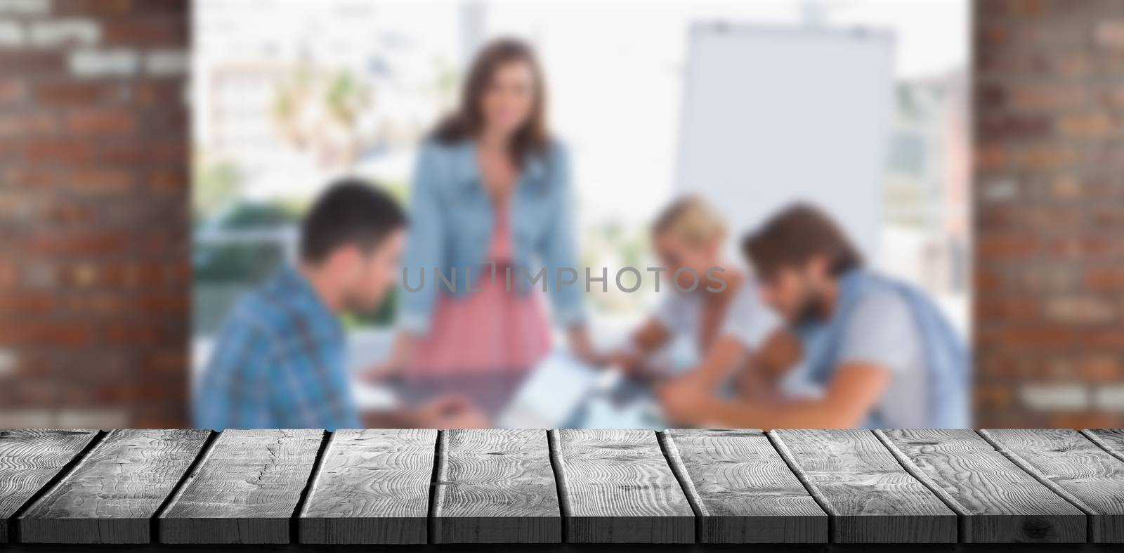 Wooden desk against team having meeting with one woman smiling at camera