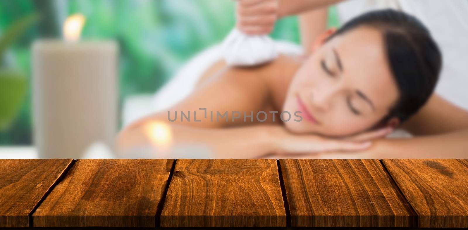 Composite image of beautiful brunette enjoying a herbal compress massage by Wavebreakmedia