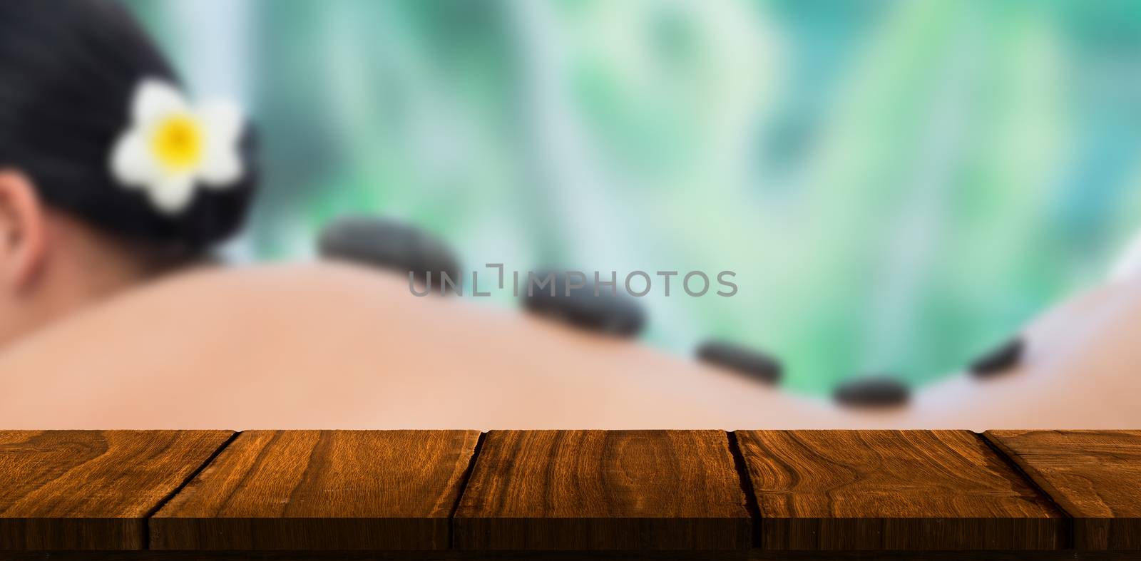 Beautiful brunette enjoying a hot stone massage against wooden desk