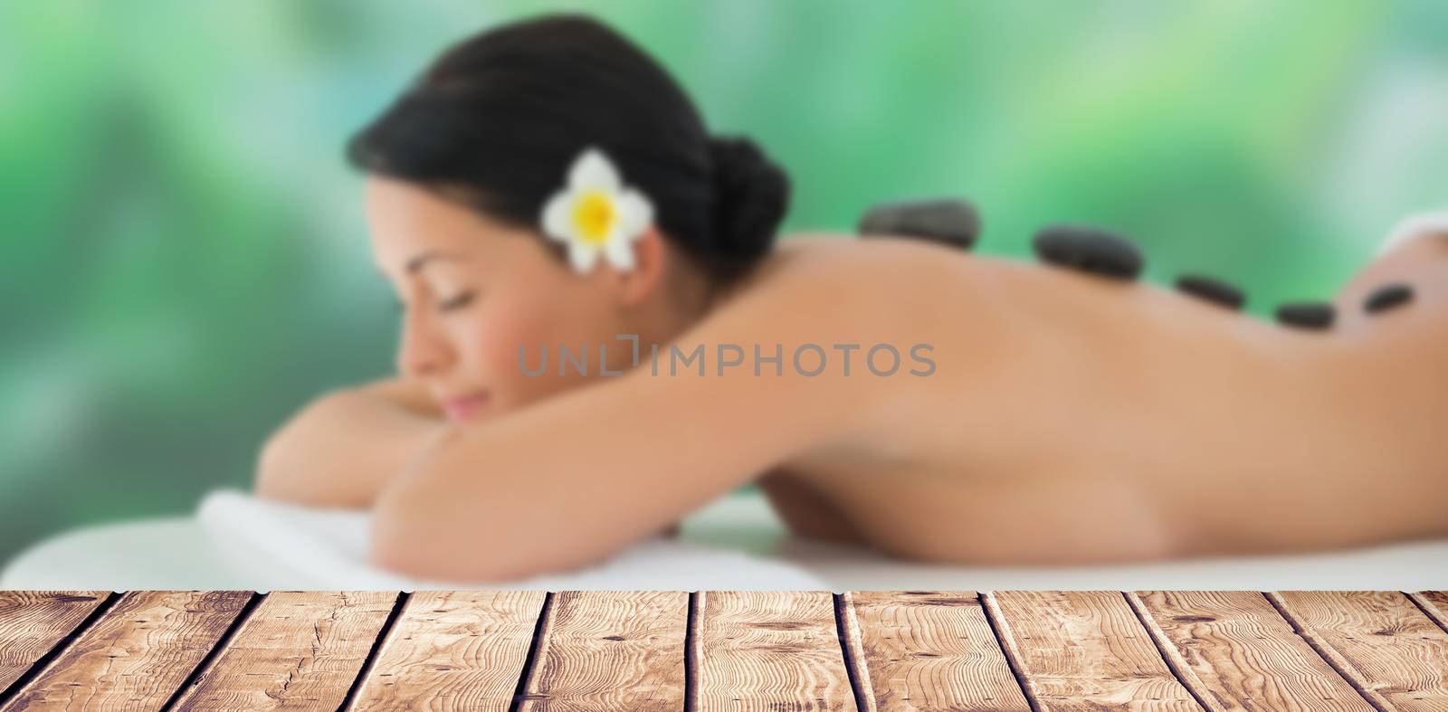 Composite image of beautiful brunette relaxing on massage table  by Wavebreakmedia