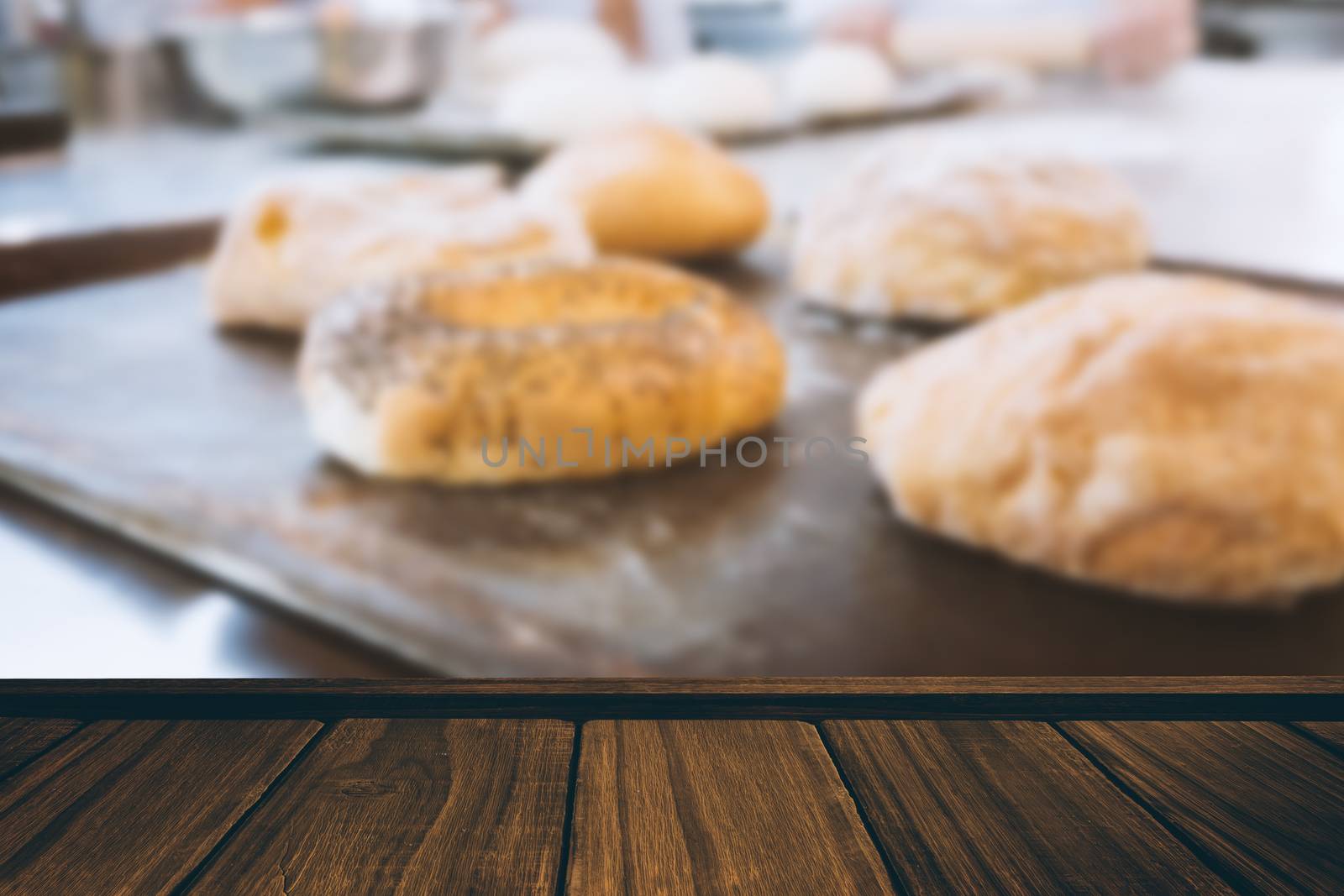 Close-up of wooden flooring against co-workers making bagels and bread together