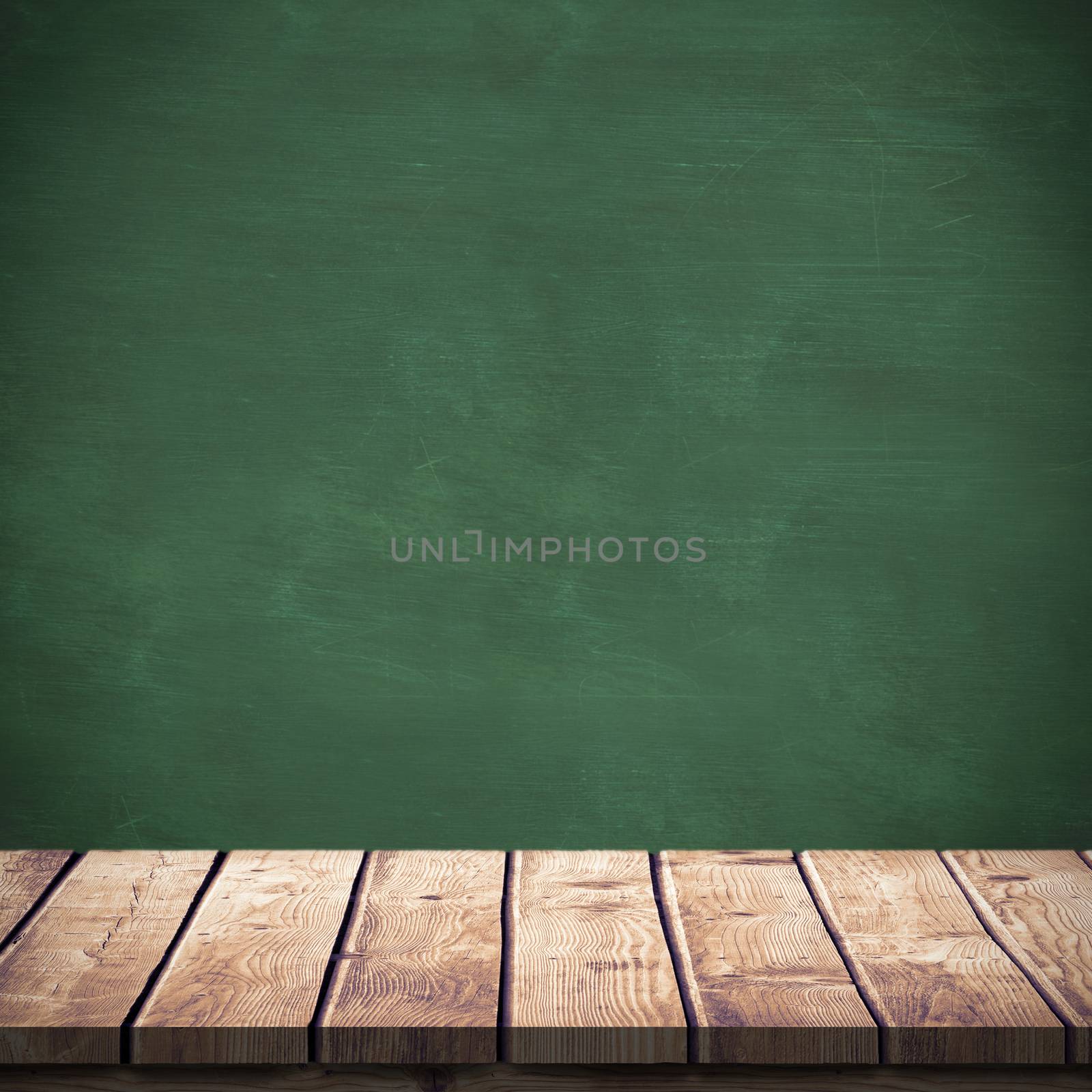 Wooden table against green chalkboard