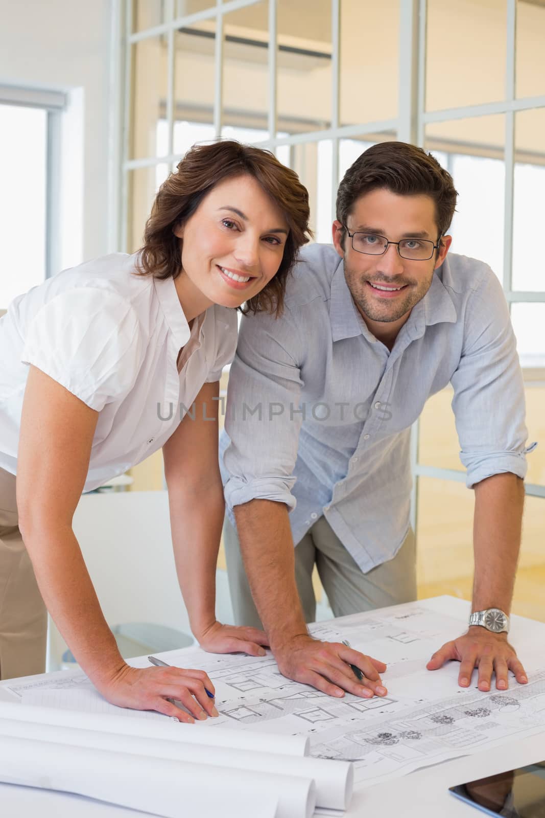 Portrait of two young business people working on blueprints at the office