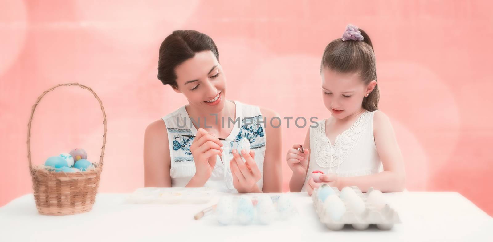 Mother and daughter painting easter eggs against background of colors
