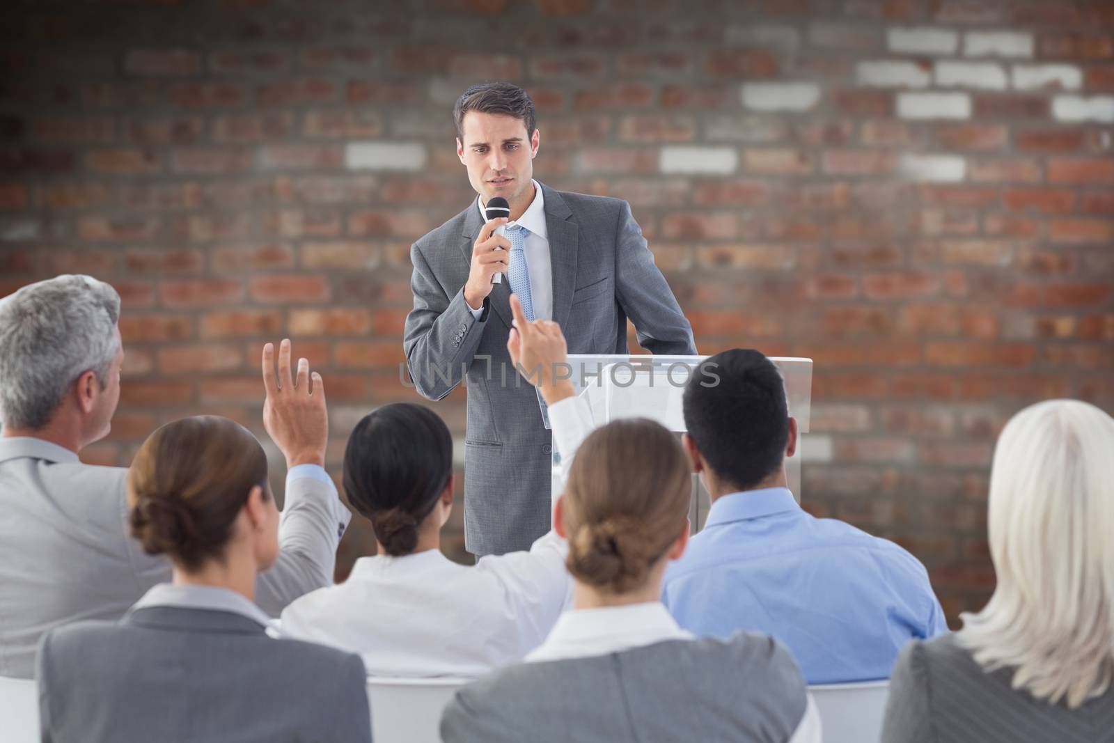 Businessman doing speech during meeting  against brick wall