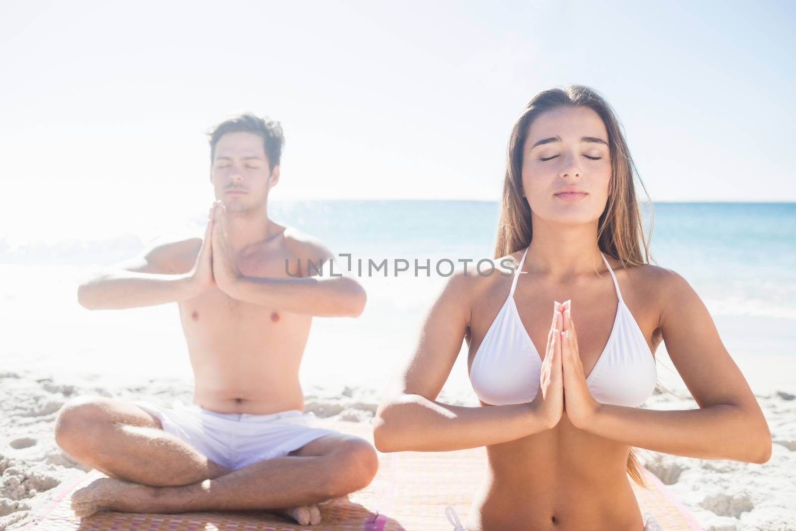  Happy couple doing yoga on the beach