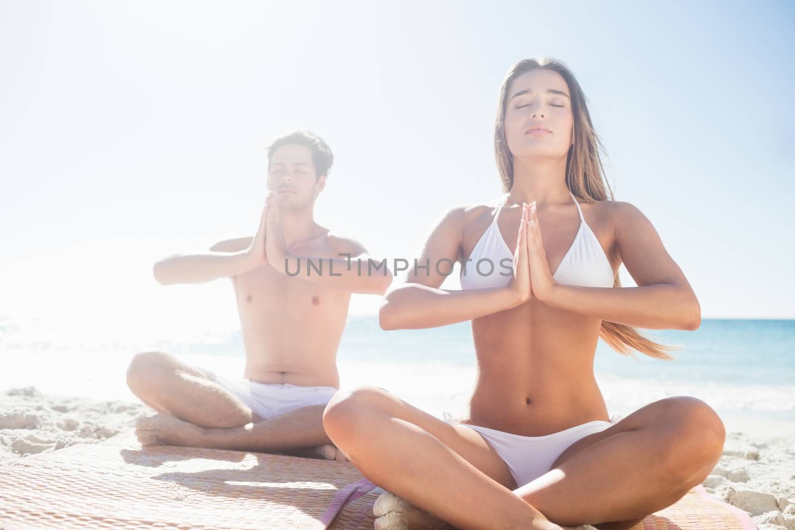  Happy couple doing yoga on the beach